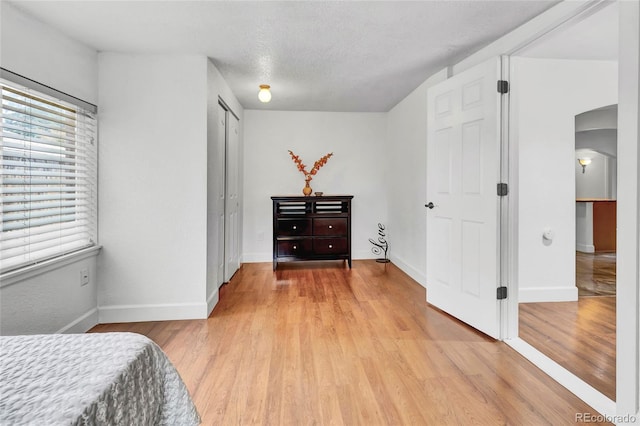 bedroom with a textured ceiling, a closet, and light wood-type flooring