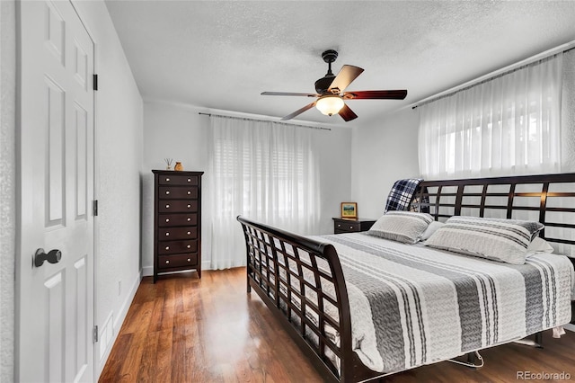 bedroom with ceiling fan, dark hardwood / wood-style flooring, and a textured ceiling