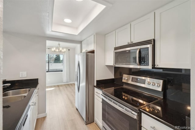 540 S Forest St Unit 3-204, Denver, CO 80246 - kitchen with appliances with stainless steel finishes, dark countertops, a sink, an inviting chandelier, and a tray ceiling