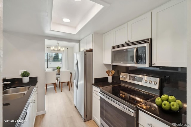540 S Forest St Unit 3-204, Denver, CO 80246 - kitchen featuring a sink, a raised ceiling, an inviting chandelier, stainless steel appliances, and white cabinetry