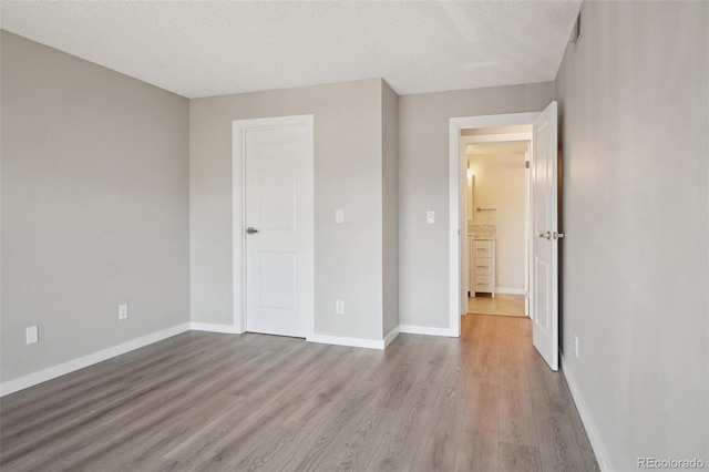 540 S Forest St Unit 3-204, Denver, CO 80246 - unfurnished bedroom featuring a textured ceiling, baseboards, and wood finished floors