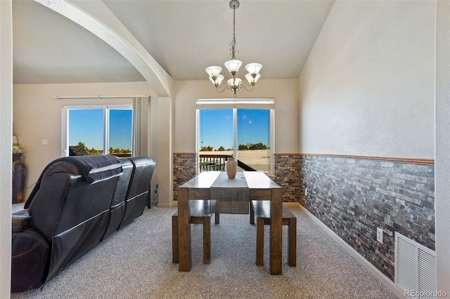 17950 Cumbres Rd, Peyton, CO 80831 - carpeted dining room featuring a chandelier, wainscoting, arched walkways, and vaulted ceiling