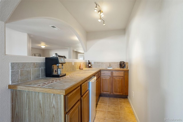 17950 Cumbres Rd, Peyton, CO 80831 - kitchen with tasteful backsplash, light tile patterned floors, tile countertops, a sink, and arched walkways