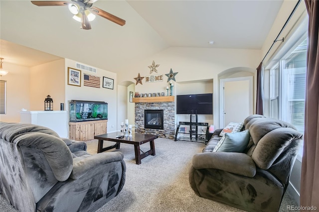 living room featuring a stone fireplace, carpet flooring, vaulted ceiling, and ceiling fan