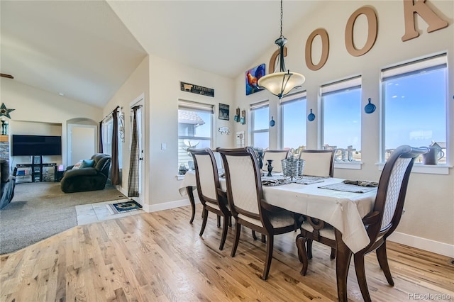 dining space with light hardwood / wood-style floors and high vaulted ceiling