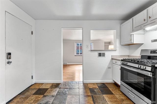 1535 Hudson St Unit 1, Denver, CO 80220 - kitchen with stainless steel gas range, stone tile flooring, baseboards, and under cabinet range hood