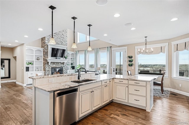 kitchen featuring sink, a kitchen island with sink, stainless steel dishwasher, light stone counters, and plenty of natural light