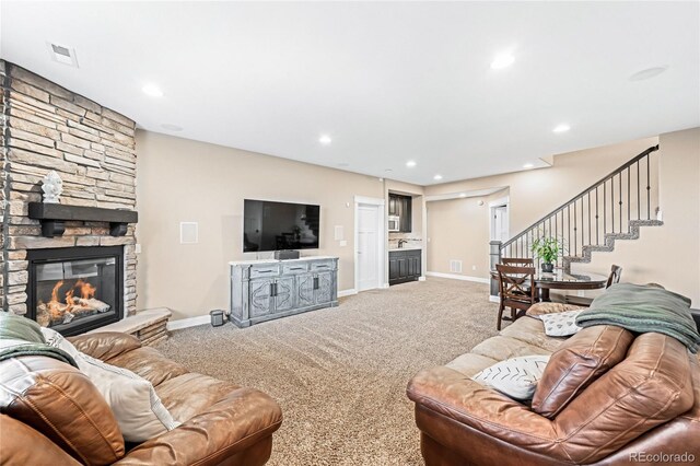 carpeted living room with a stone fireplace