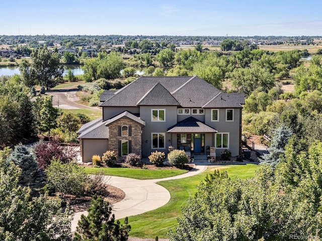 view of front facade with stucco siding, a front lawn, stone siding, roof with shingles, and concrete driveway