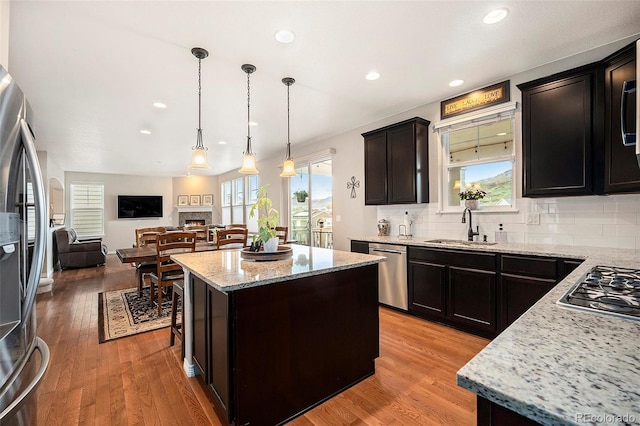 6173 Eldora St, Golden, CO 80403 - kitchen with appliances with stainless steel finishes, a sink, light stone countertops, a center island, and a warm lit fireplace
