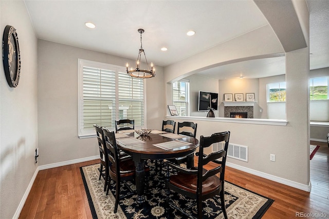 6173 Eldora St, Golden, CO 80403 - dining room featuring a lit fireplace, baseboards, wood finished floors, a chandelier, and recessed lighting