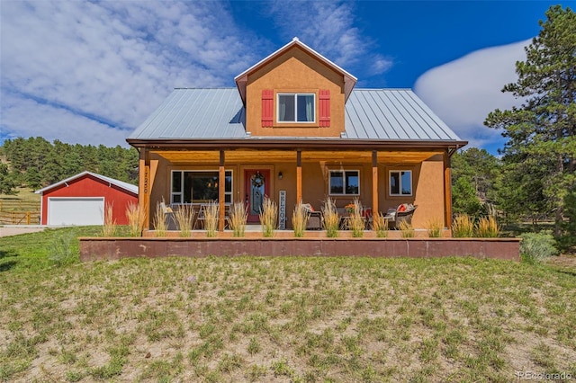 view of front facade featuring a front yard, a porch, a garage, and an outdoor structure