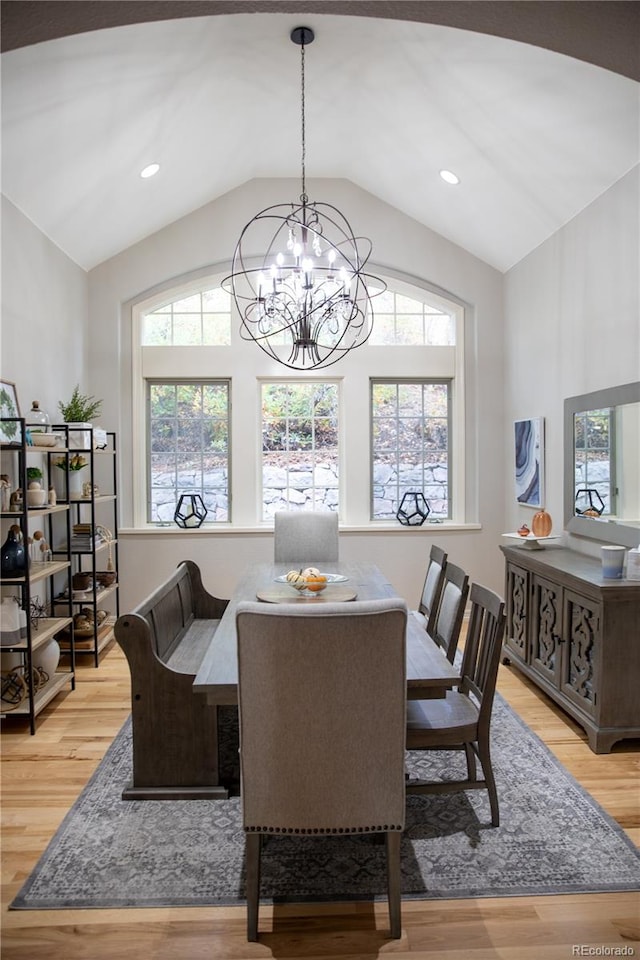 dining space with lofted ceiling, light wood-type flooring, and an inviting chandelier