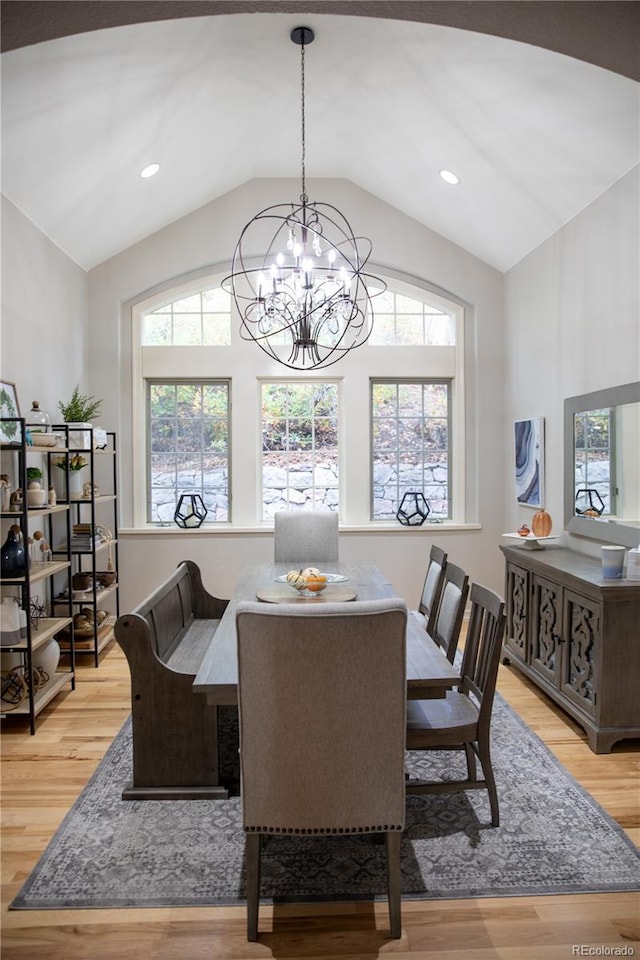 dining space with vaulted ceiling, a notable chandelier, and light wood-type flooring
