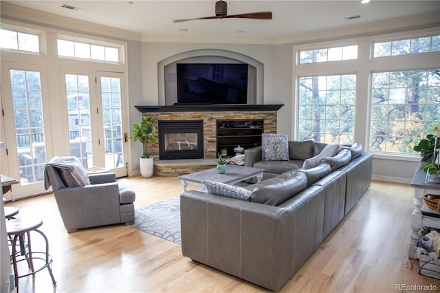 living room with light hardwood / wood-style flooring, ceiling fan, a fireplace, and crown molding