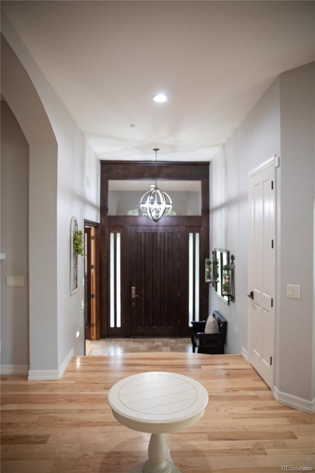 foyer with recessed lighting, light wood-type flooring, baseboards, and an inviting chandelier