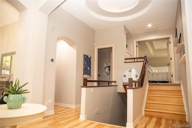 interior space with arched walkways, a raised ceiling, wood finished floors, and visible vents