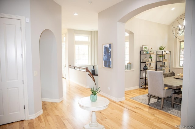 interior space featuring arched walkways, wood finished floors, baseboards, and recessed lighting