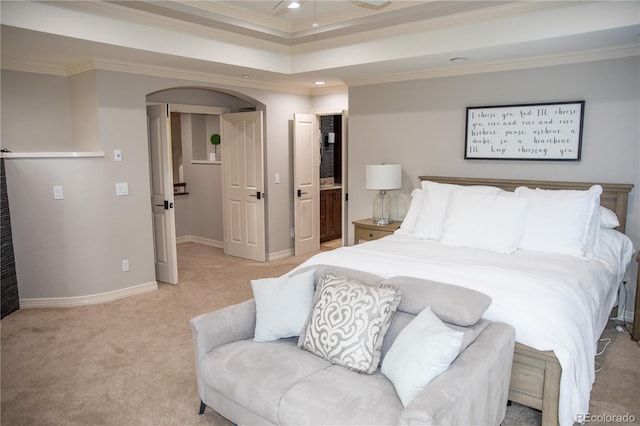 carpeted bedroom featuring ornamental molding, a tray ceiling, and connected bathroom