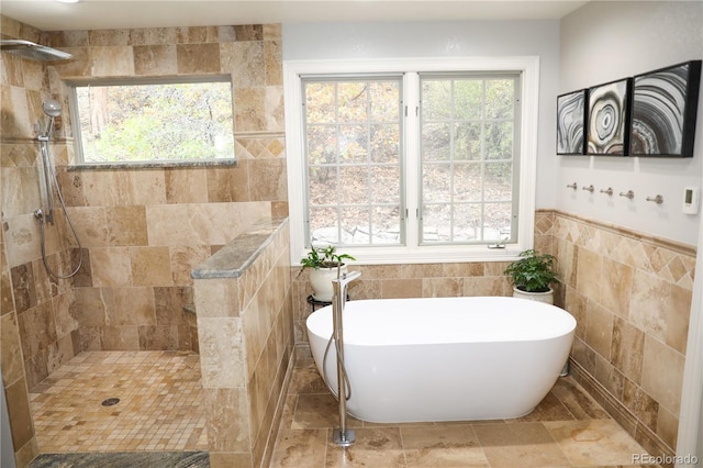 bathroom with tile walls, wainscoting, a freestanding bath, and tiled shower