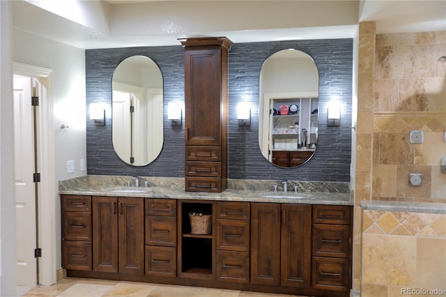 full bathroom featuring a tile shower, a sink, and double vanity