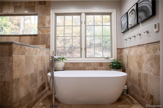 bathroom with tile walls, plenty of natural light, and a soaking tub