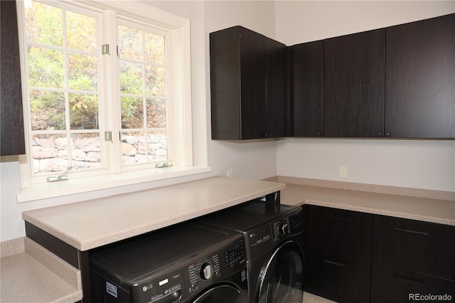 clothes washing area featuring cabinet space and washer and clothes dryer
