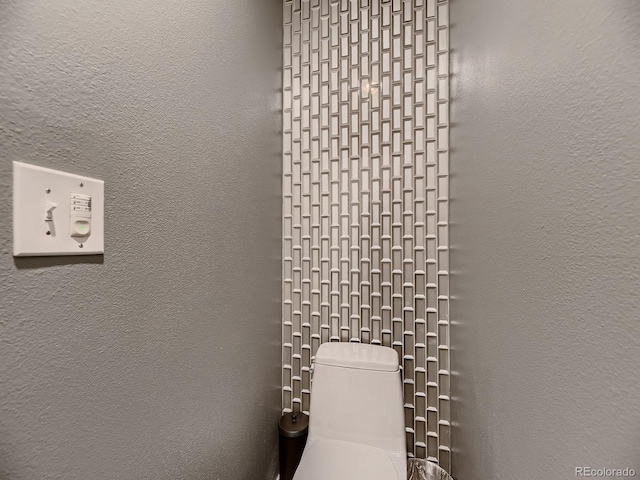 bathroom featuring toilet and a textured wall