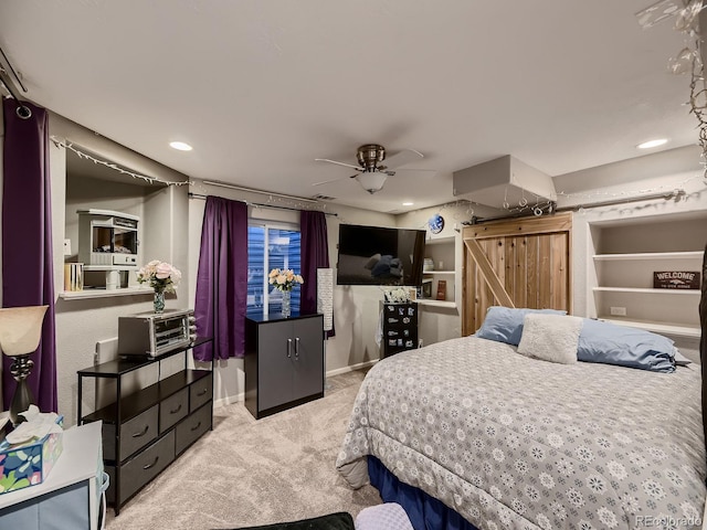 bedroom with recessed lighting, light colored carpet, baseboards, and a barn door