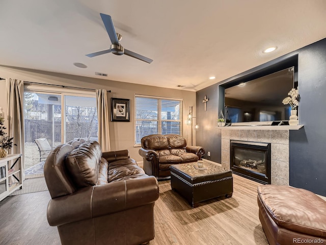 living area featuring baseboards, visible vents, ceiling fan, wood finished floors, and a fireplace