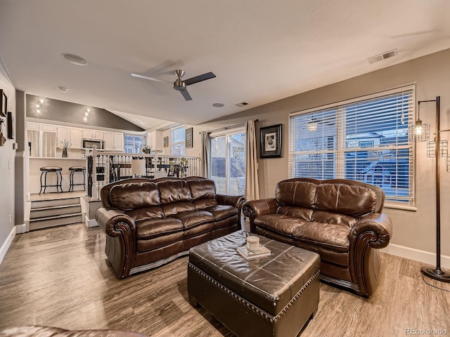 living area featuring lofted ceiling, visible vents, ceiling fan, and wood finished floors