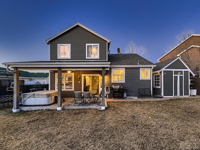 back of house featuring a storage shed, a hot tub, a patio, an outbuilding, and fence