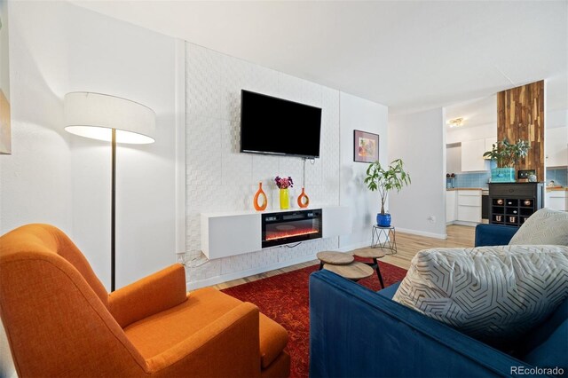 living area with light wood finished floors and a glass covered fireplace