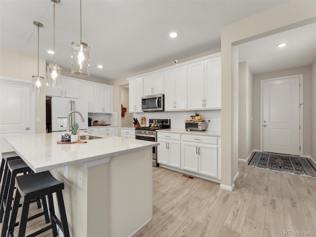 4538 Hidden Gulch Rd, Castle Rock, CO 80104 - kitchen featuring a breakfast bar area, hanging light fixtures, a sink, white cabinetry, and stainless steel appliances