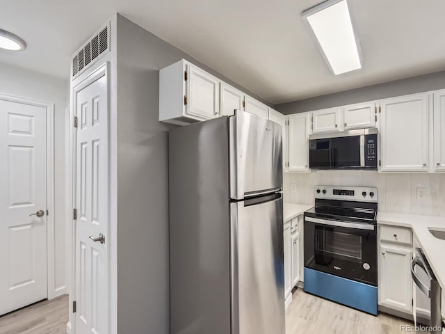 kitchen featuring stainless steel appliances, light hardwood / wood-style flooring, and white cabinets