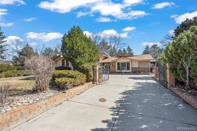 view of front of home featuring brick siding, concrete driveway, and a gate