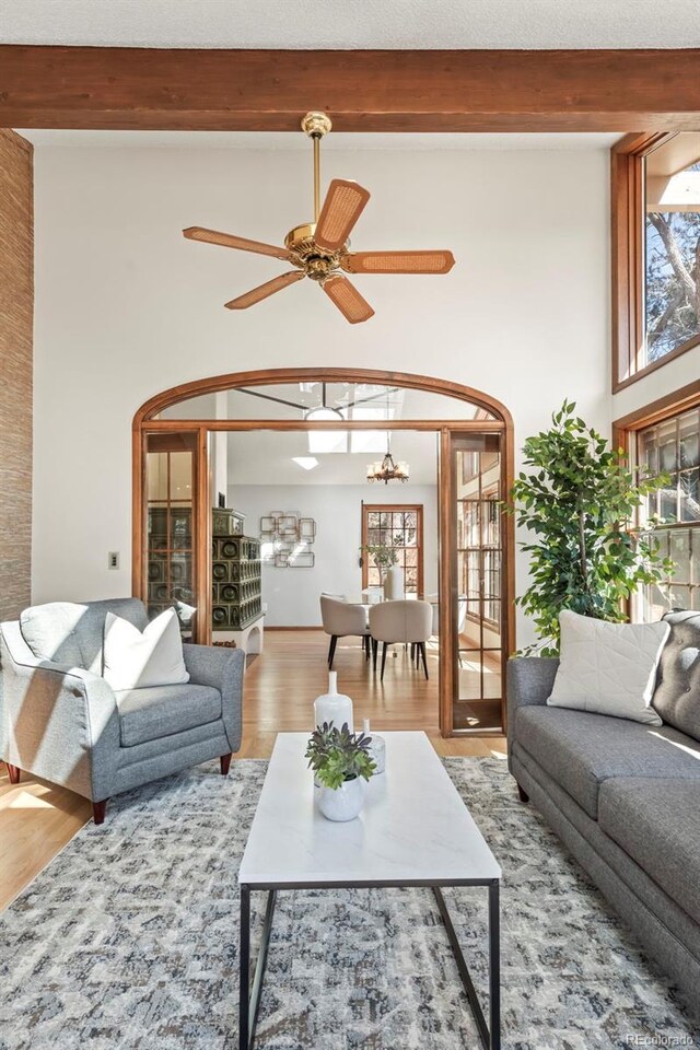 living room with beamed ceiling, plenty of natural light, wood finished floors, and a high ceiling