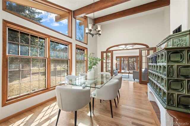 dining space featuring beam ceiling, light wood-style floors, baseboards, and a chandelier