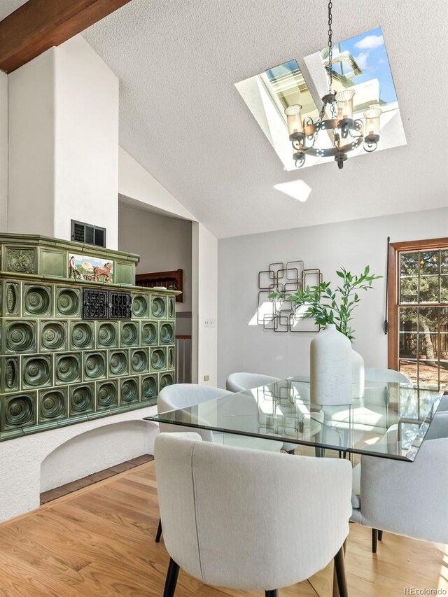 dining space featuring vaulted ceiling with skylight, a textured ceiling, and wood finished floors