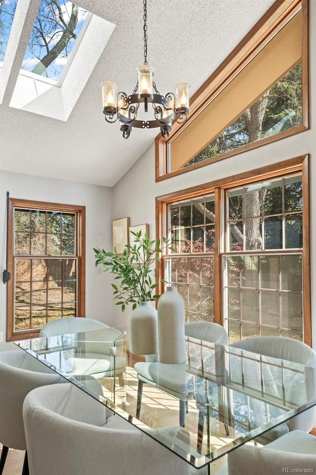 dining room featuring a notable chandelier, vaulted ceiling with skylight, and a textured ceiling