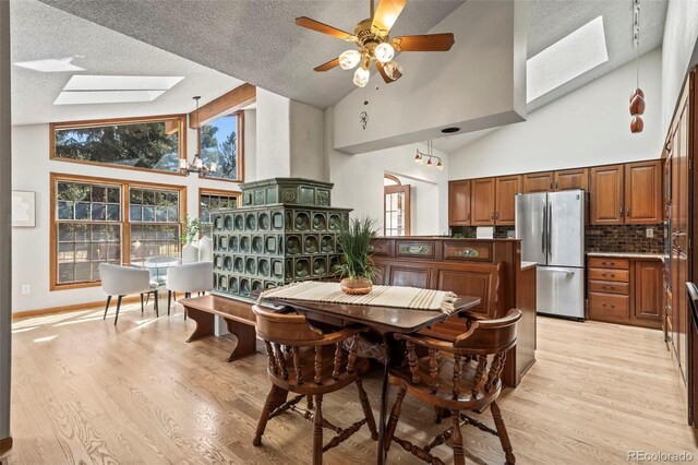 dining room featuring a skylight, light wood-type flooring, and a textured ceiling