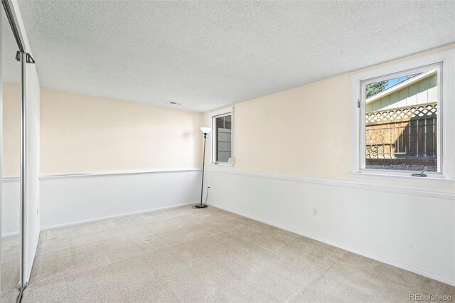 carpeted empty room featuring a textured ceiling and baseboards