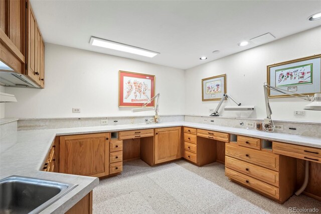 interior space with a sink, recessed lighting, brown cabinetry, light countertops, and built in study area