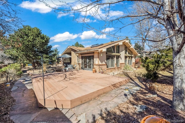 rear view of house featuring french doors, brick siding, and a wooden deck