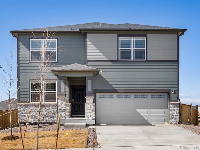 view of front of home featuring stone siding, concrete driveway, an attached garage, and fence