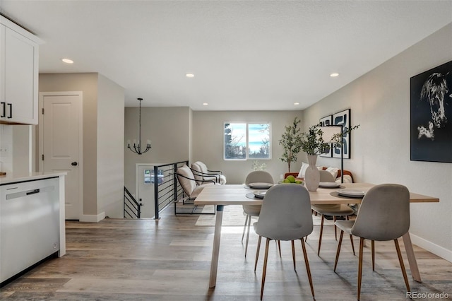 dining space with light hardwood / wood-style floors and an inviting chandelier