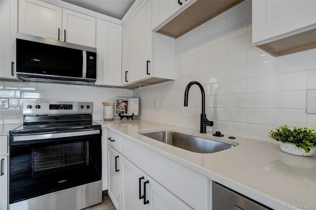 kitchen featuring stainless steel appliances, white cabinetry, tasteful backsplash, and sink