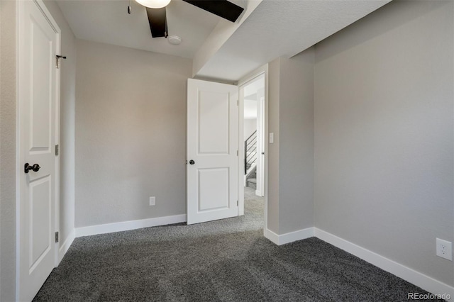 interior space with ceiling fan and dark carpet