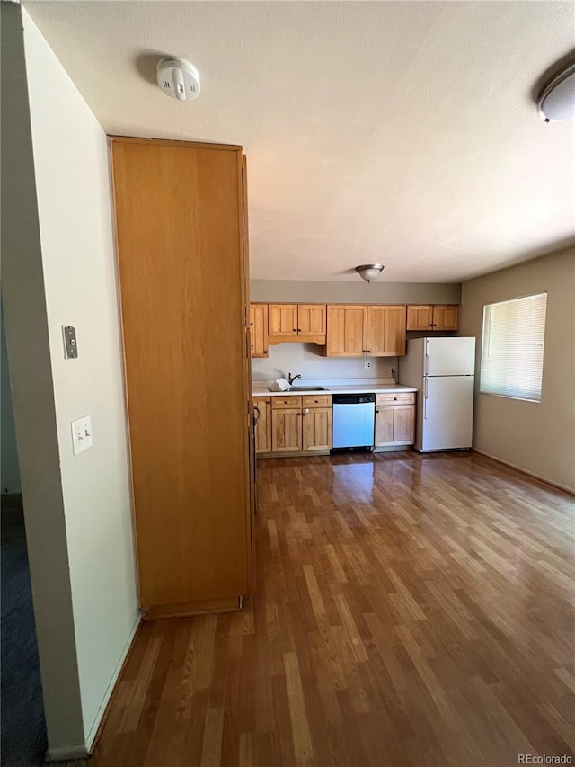 kitchen with white fridge, stainless steel dishwasher, dark hardwood / wood-style floors, and sink