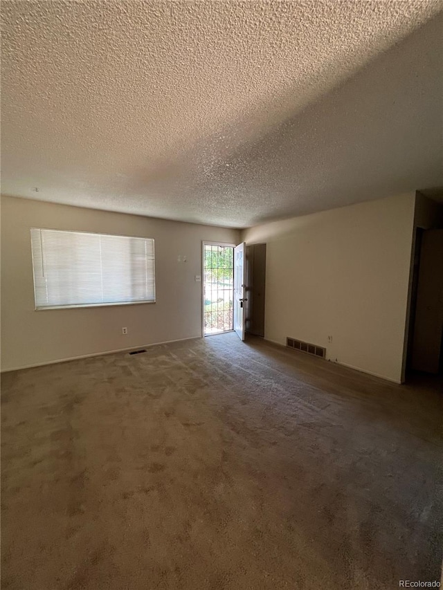 unfurnished room with carpet and a textured ceiling